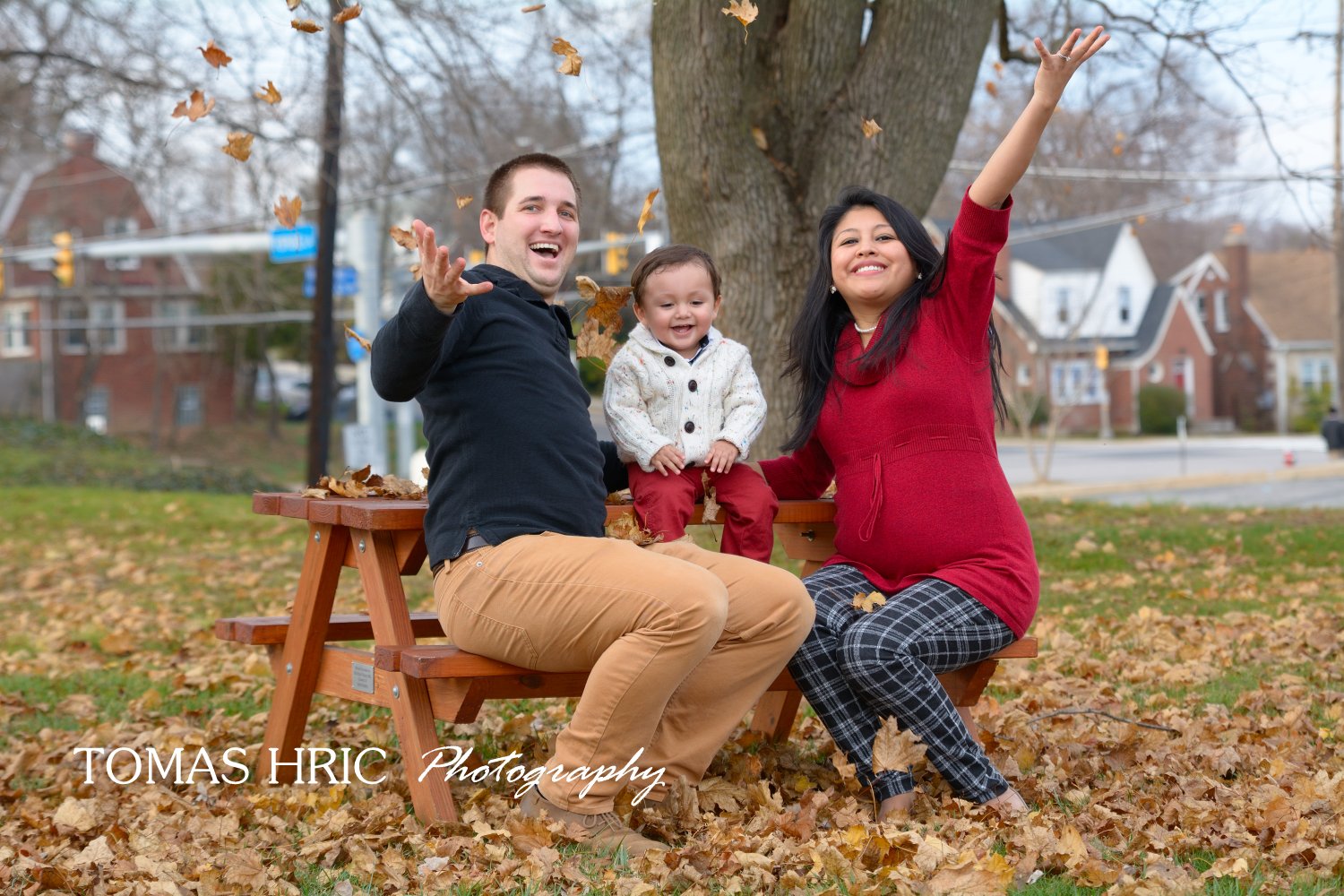 family photo session mother father and son throwing leaves in the air in the fall